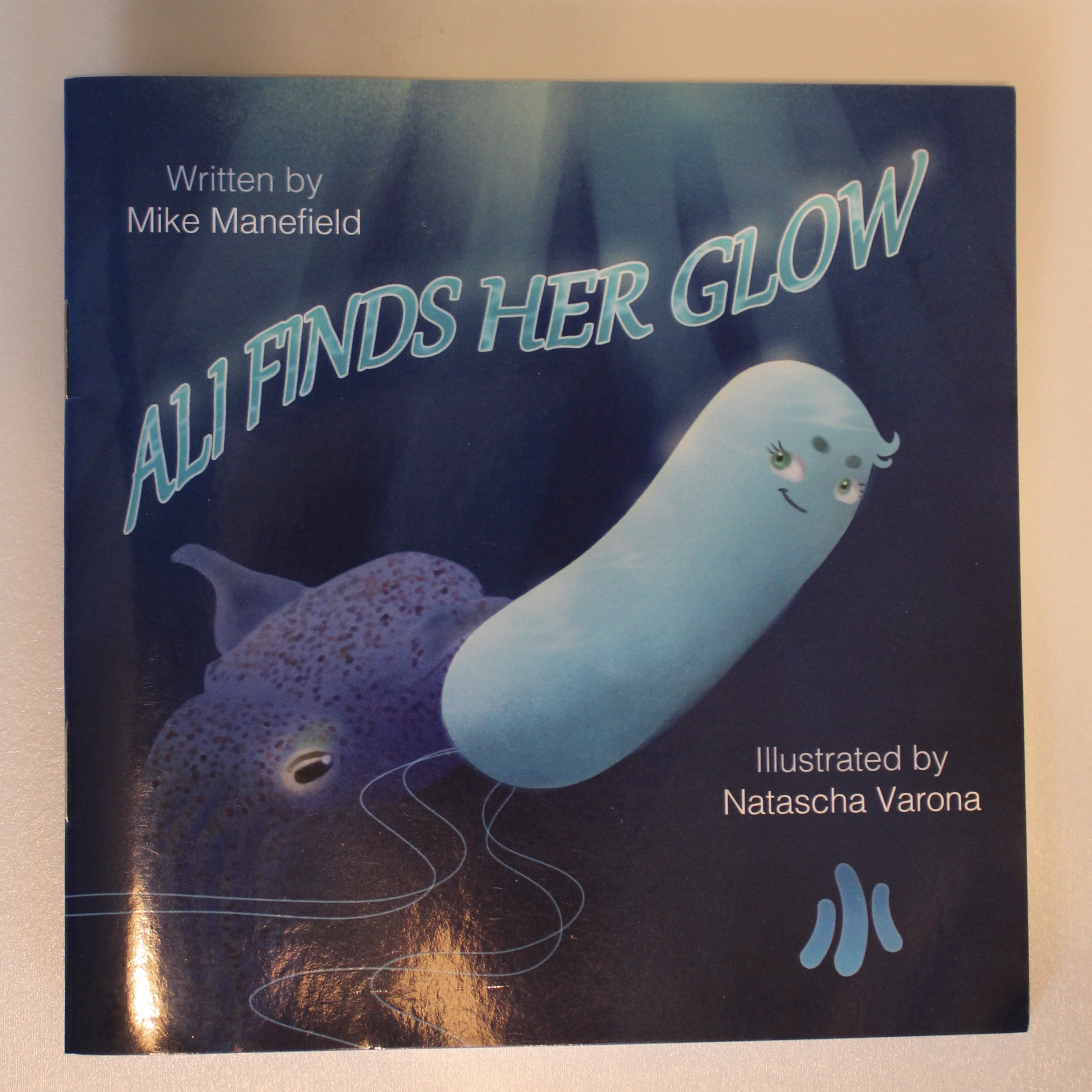 children's book cover with blue bioluminescent bacteria that says Ali Finds Her Glow by Mike Manefield and illustrated by Natascha Varona