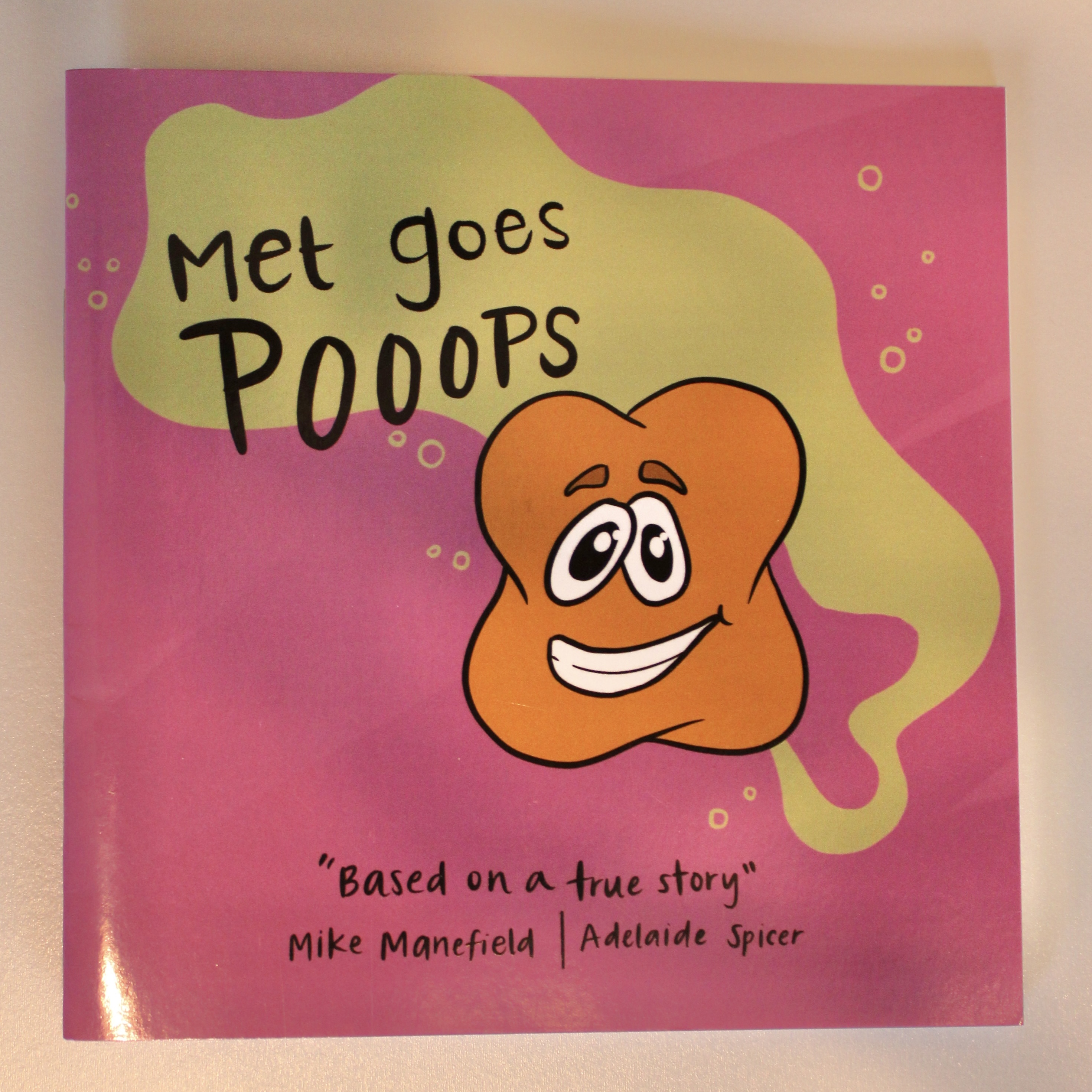 children's book cover with pink background and orange archaea cell that says Met Goes Pooops by Mike Manefield and illustrated by Adelaide Spicer